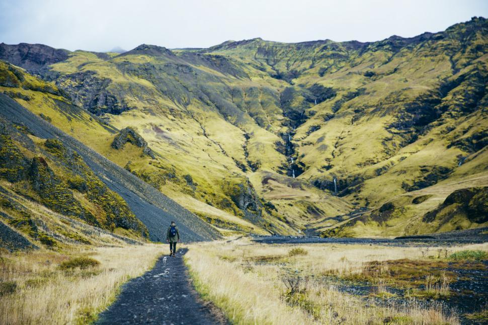 Free Image of A hiker on green fields near glacier 