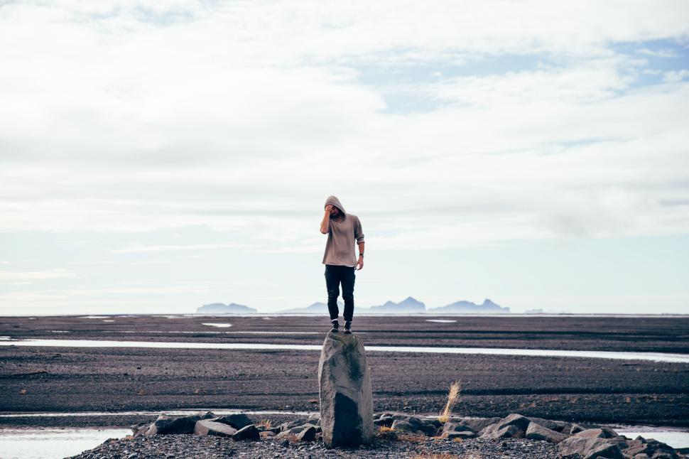 Free Image of A young Caucasian man standing on a tall rock 