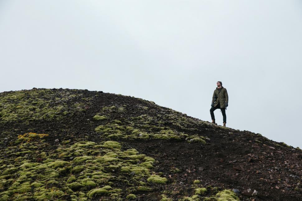 Free Image of A hiker in standing on a moss-grown rocky hill 