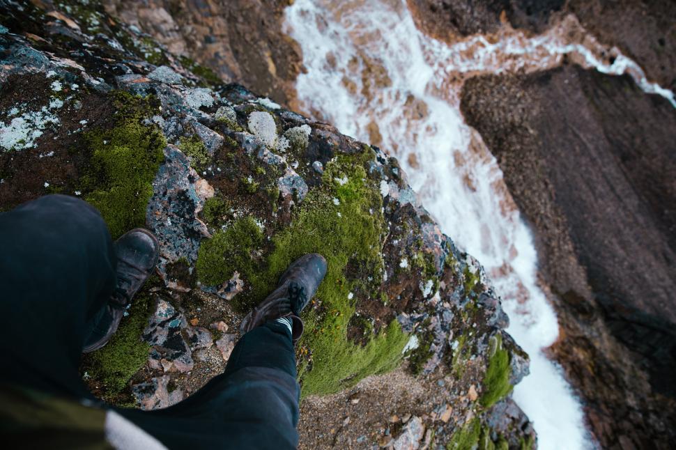 Free Image of Feet dangling over moss grown rock edge 