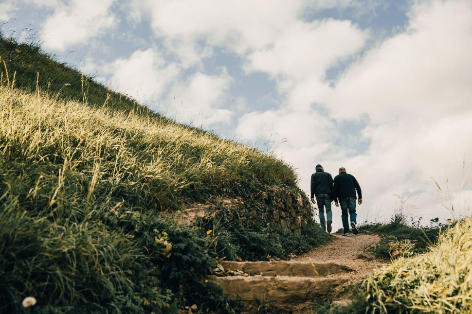 Free Image of Men hiking on grassy hills 