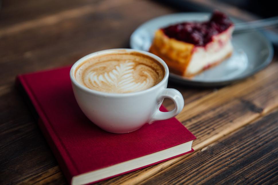 Free Image of Latte art coffee poured in a cup kept on the book 