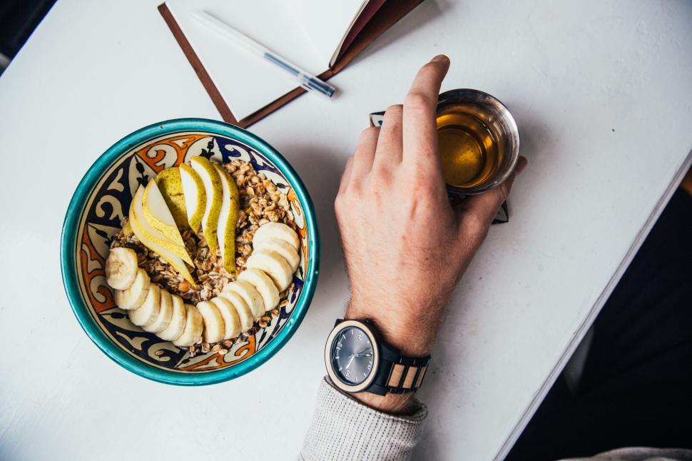 Free Image of Tea mug held in a male hand with granola in a plate 
