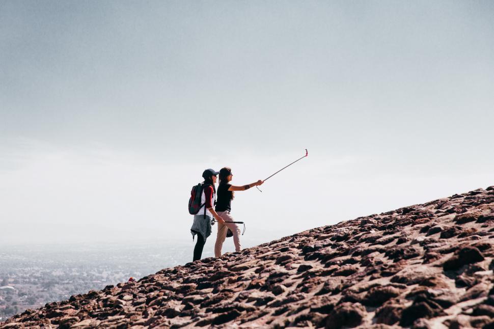 Free Image of Two young Caucasian female hikers taking selfie on a cobblestone 