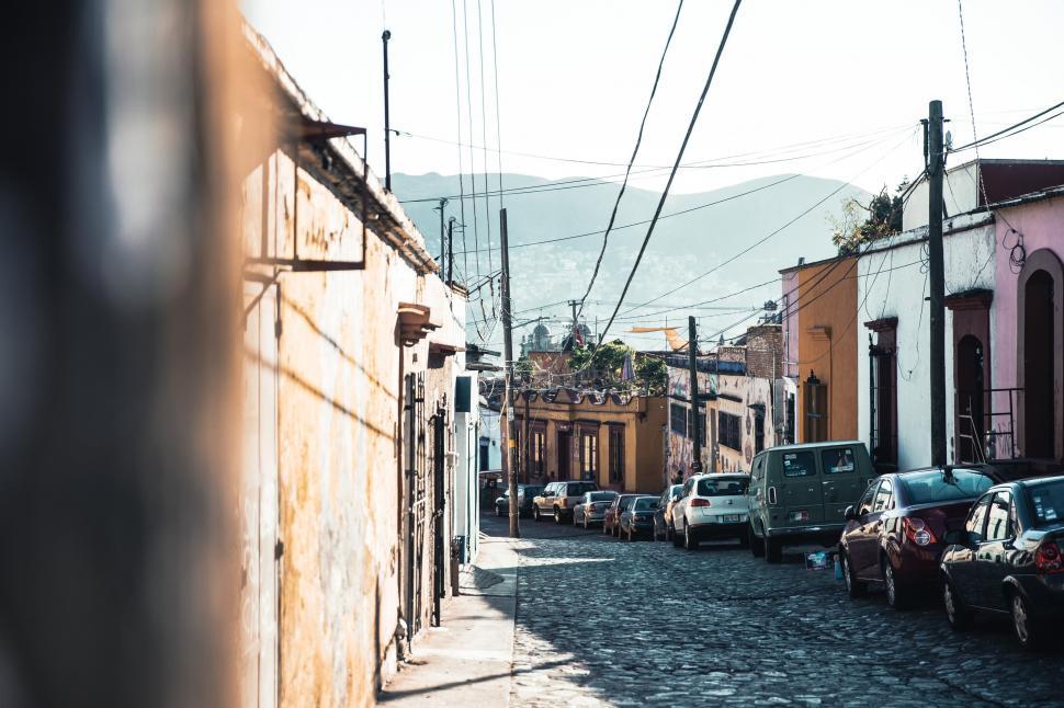 Free Image of Cars parked along cobblestone way 