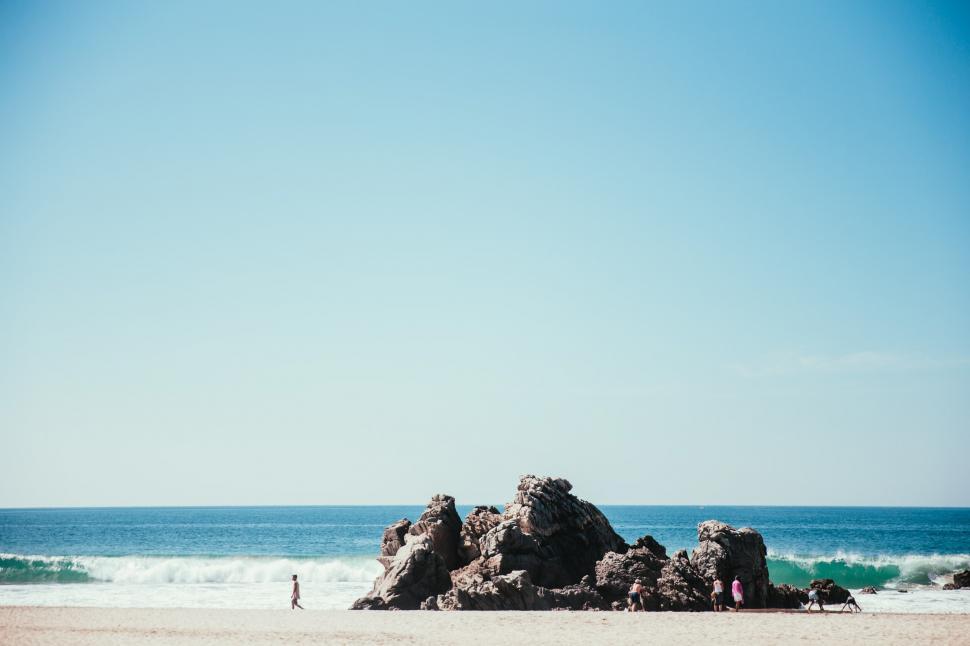 Free Image of Tourists on a rocky seashore in sunlight 