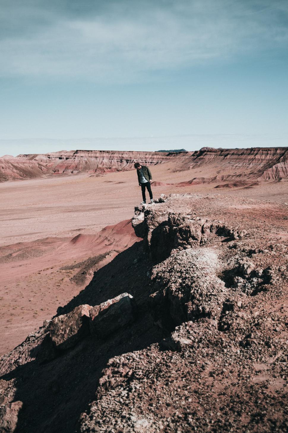 Free Image of A hiker peaks over a rocky edge 
