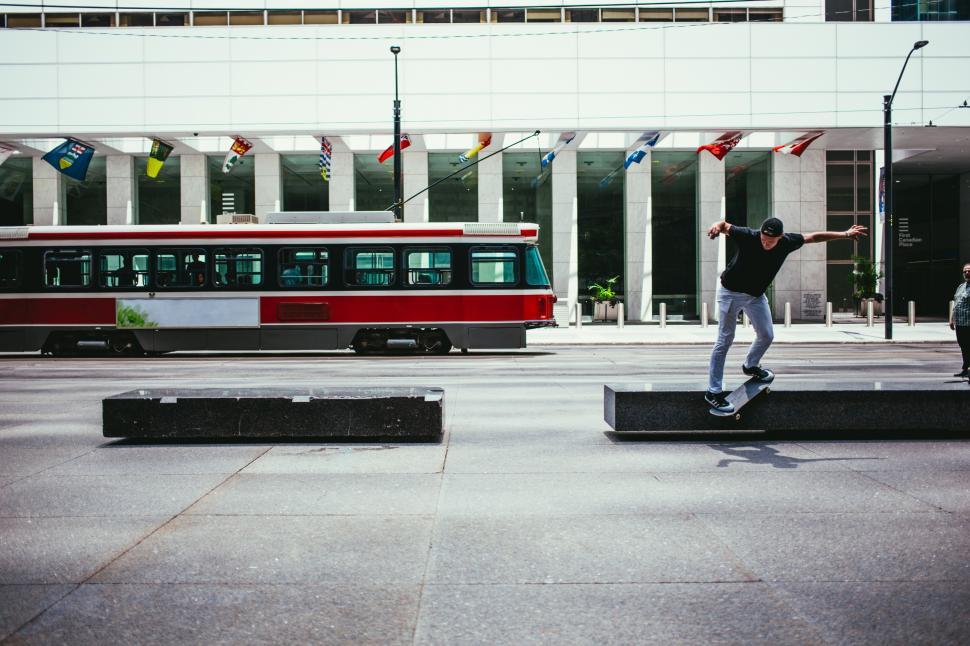 Free Image of A young Caucasian skateboarder in action near a city building 