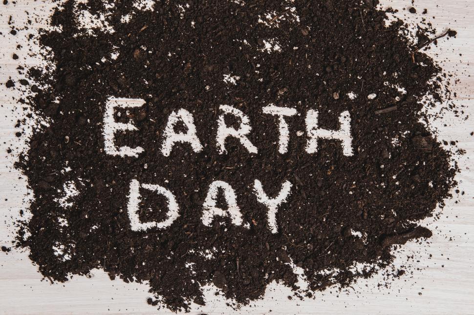 Free Image of The text  EARTH DAY  written out in dark soil on a white wooden surface 