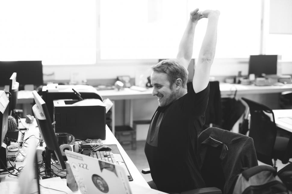 Free Image of An employee stretching as he takes a break sitting back in his c 