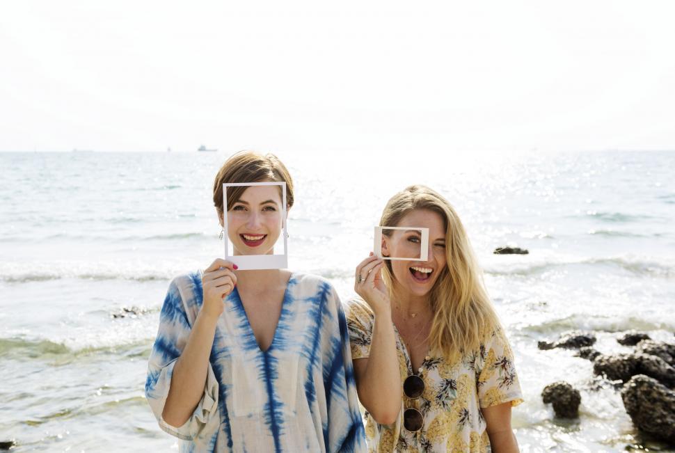 Free Image of Two young caucasian women posing with paper frame cutouts by the 