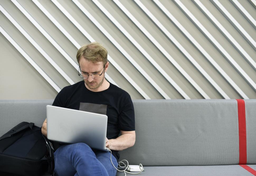 Free Image of A young man sitting on the couch working on his laptop 