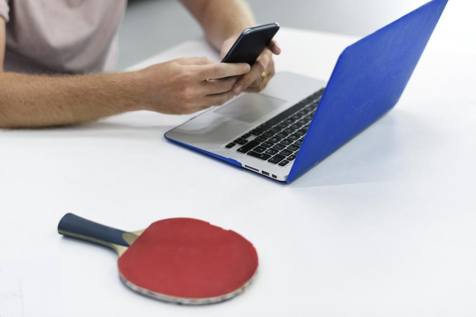 Free Image of Close up of hands holding a mobile phone over a laptop alongside 