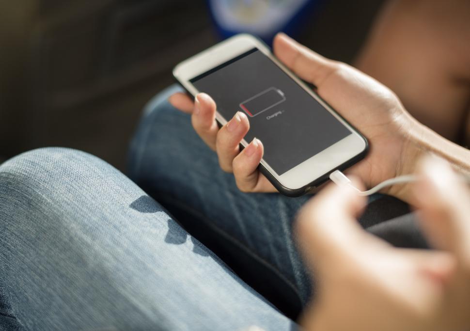 Free Image of Close up a mobile phone in a hand being charged by connecting a 