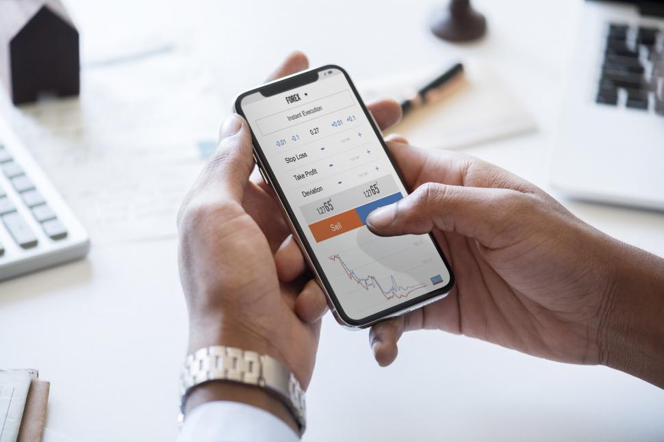 Free Image of Hands holding a mobile phone showing profit and loss data 