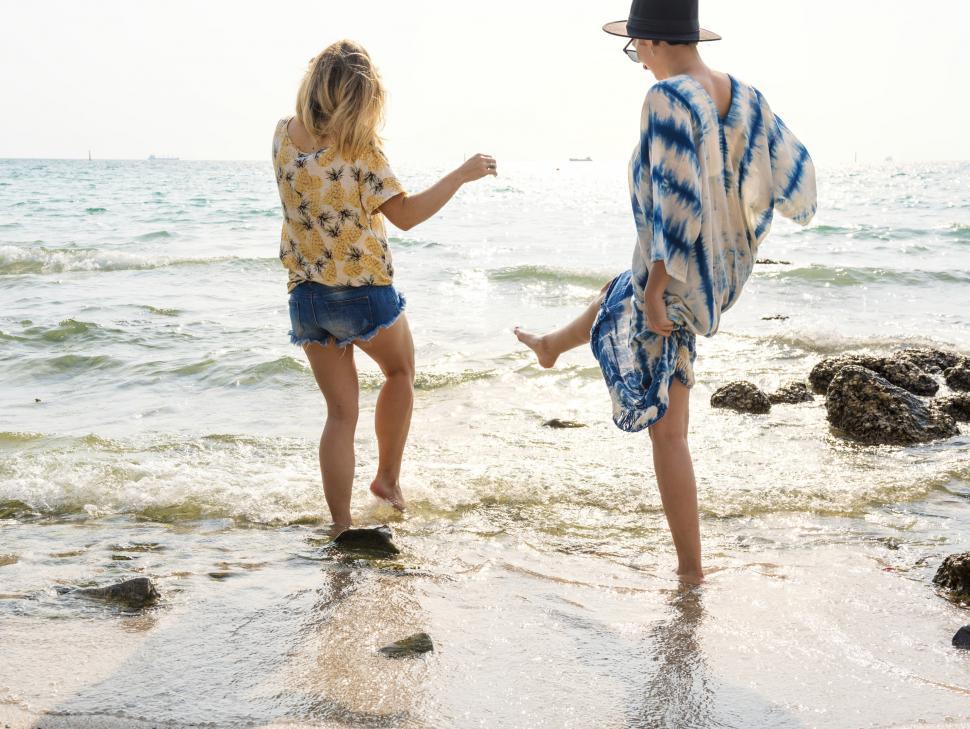 Free Image of Rear view of two women splashing seawater with their l 