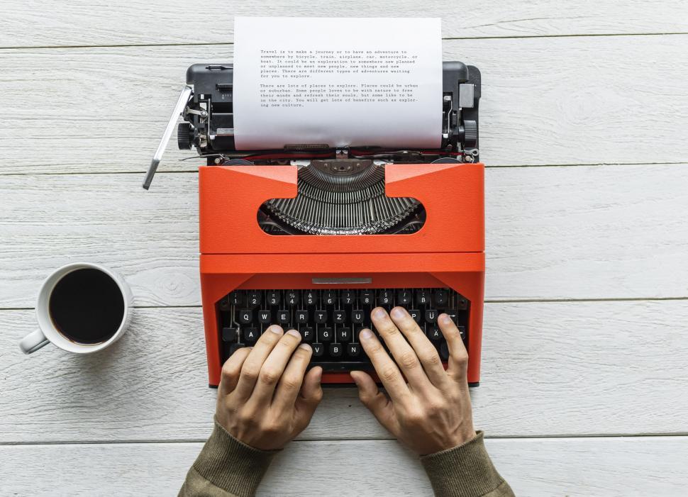 Free Image of Flay lay of hands typing on red typewriter 