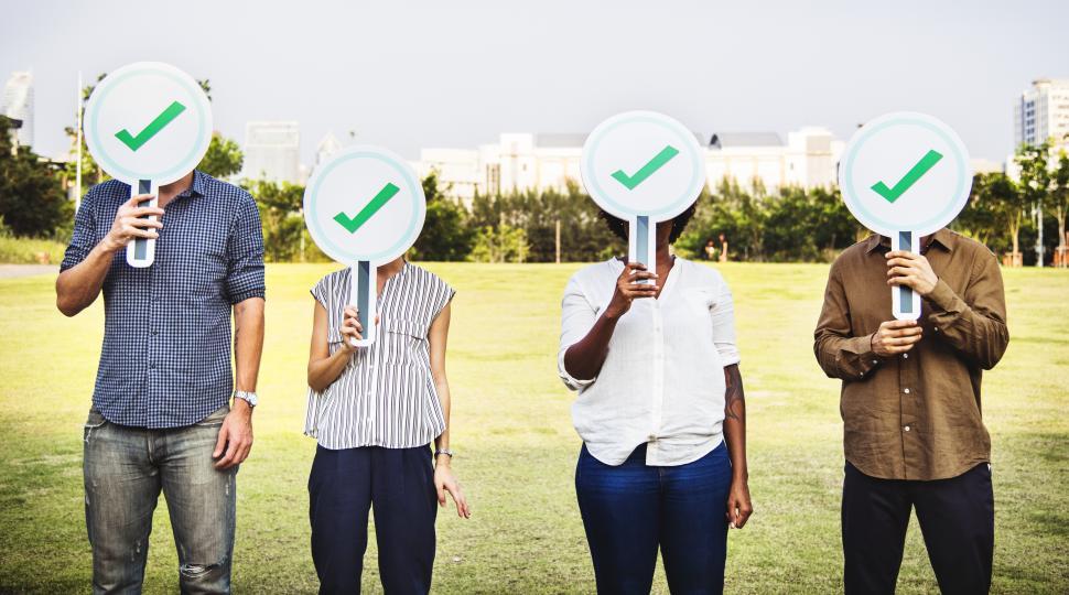 Free Image of Group of business people hiding their faces behind cardboard check mark signs 