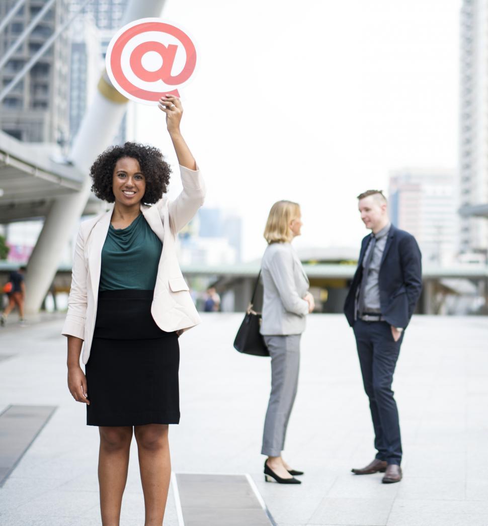 Free Image of A young African ethnicity woman with curly hair hold a cardboard at sign    in her hand high with a smile 