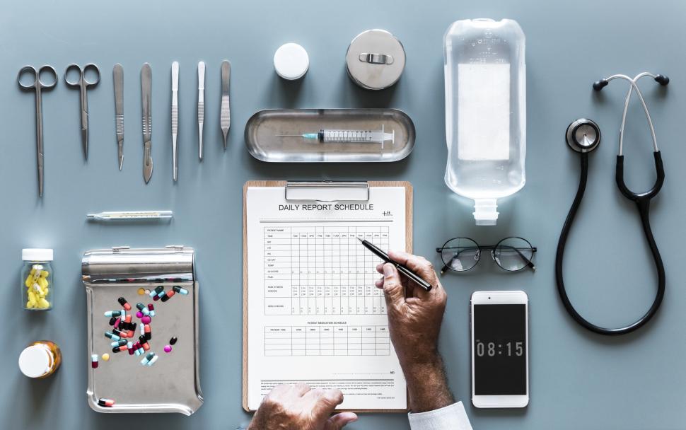 Free Image of Flat lay of doctor s hands checking daily report schedule surrounded with medicines and medical instruments 