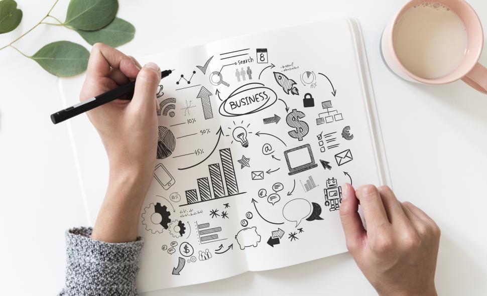 Free Image of Over the head view of financial symbols being drawn on white notebook 
