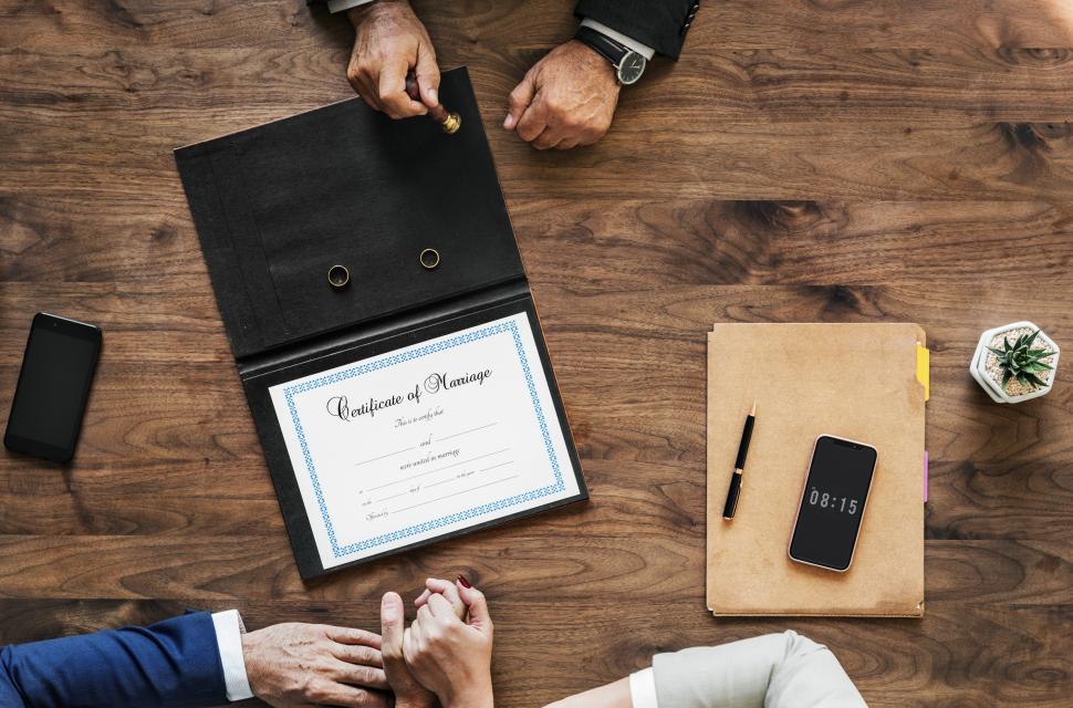 Free Image of Flat lay of of a marriage certificate with a couple s hand in hand 