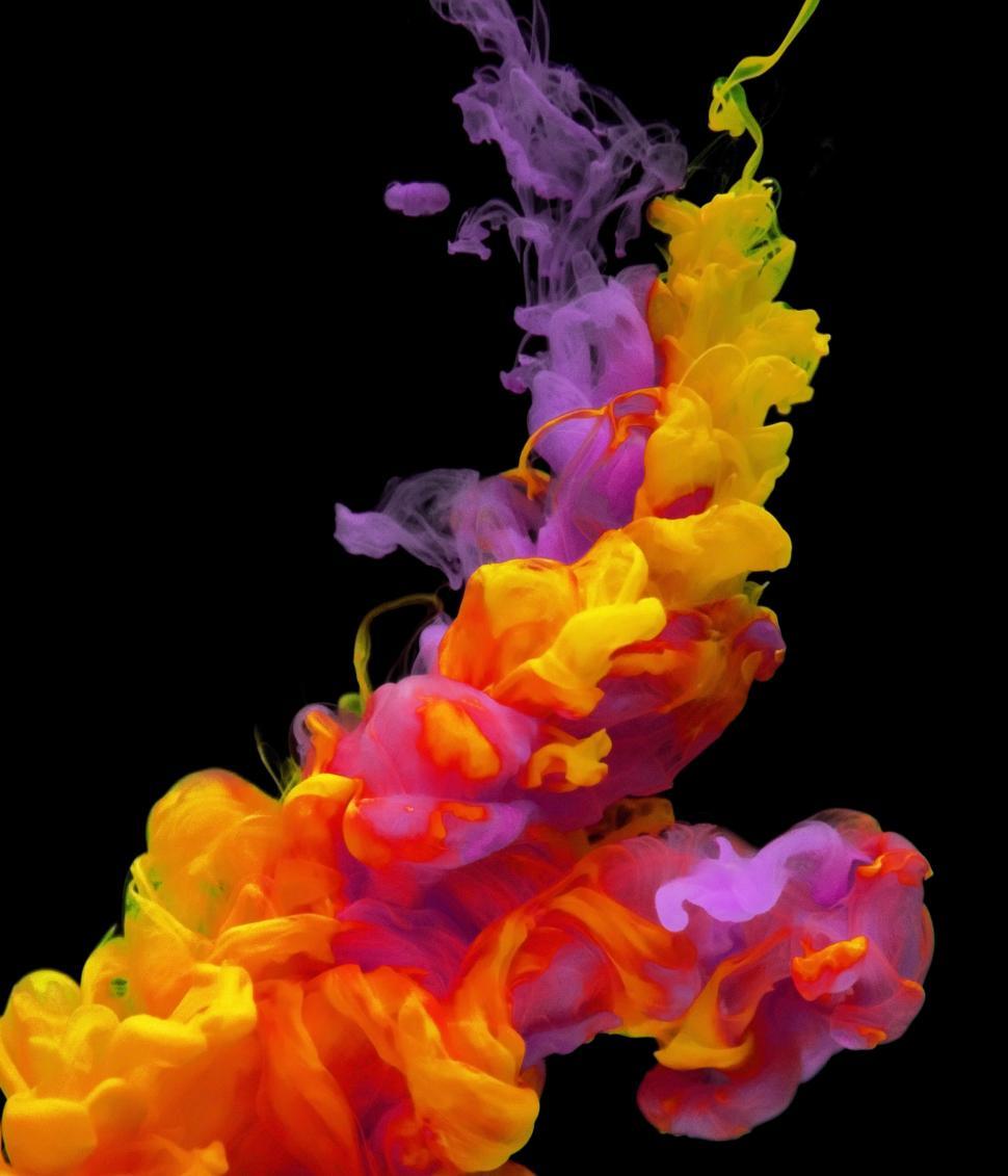 Free Image of An abstract pattern of red, yellow and purple ink swirling in water 