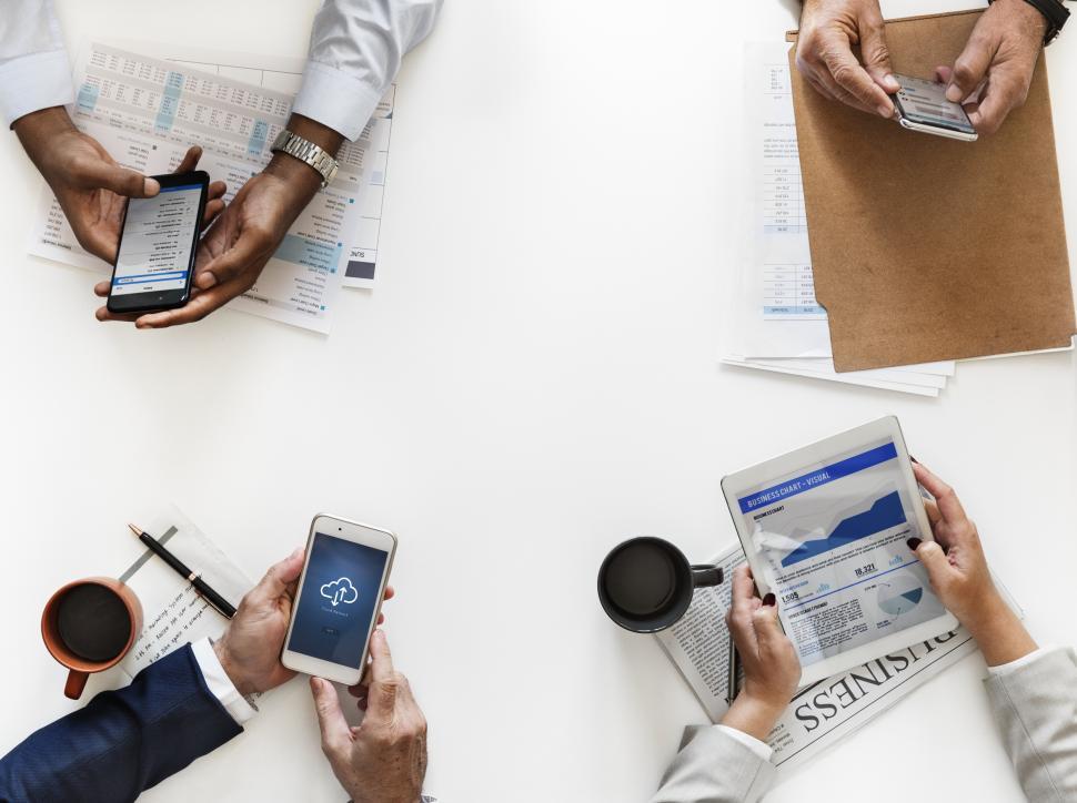 Free Image of Overhead view of four people operating mobile phones on a meeting table 