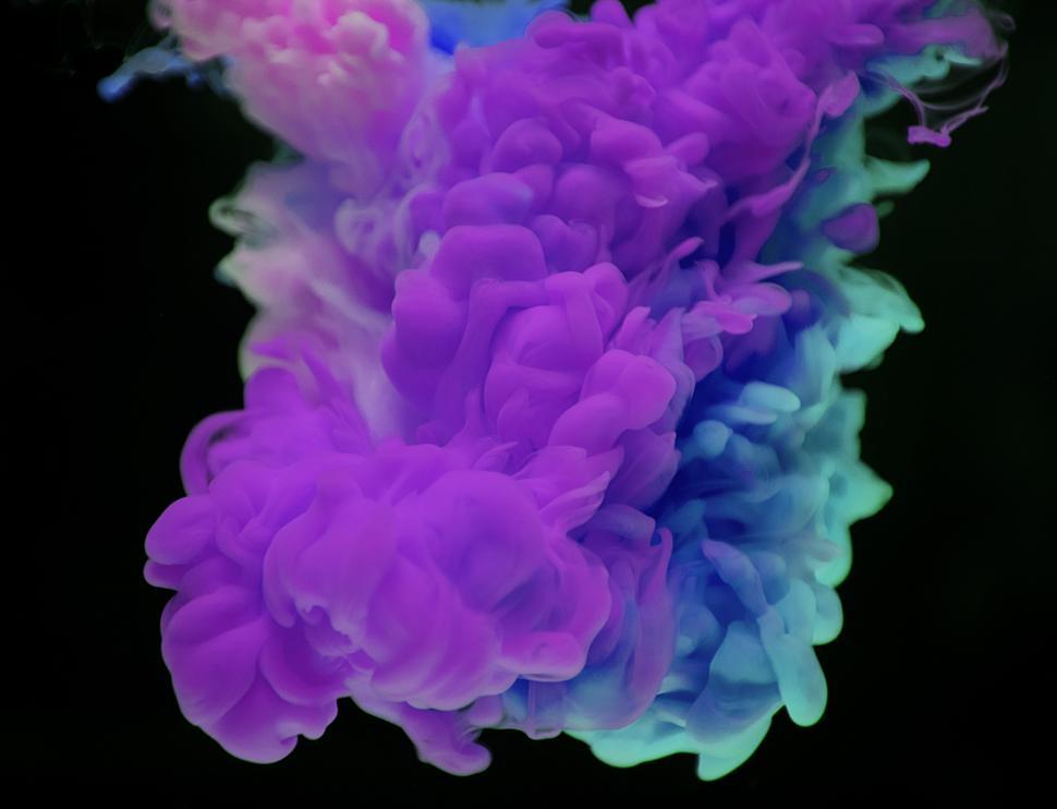 Free Image of An abstract pattern of green, blue and magenta ink swirling in water 