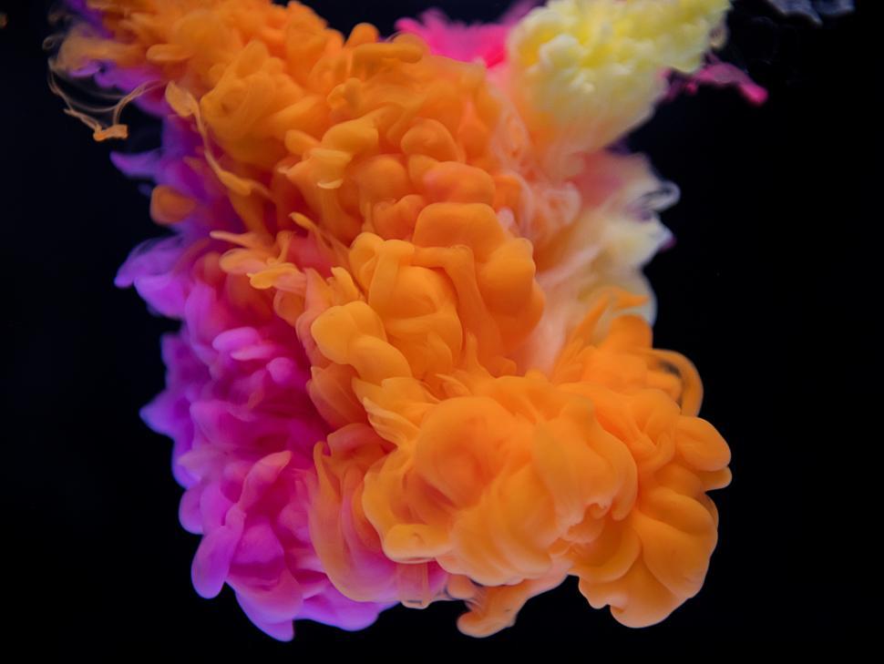 Free Image of An abstract pattern of yellow, magenta and orange ink swirling in water 