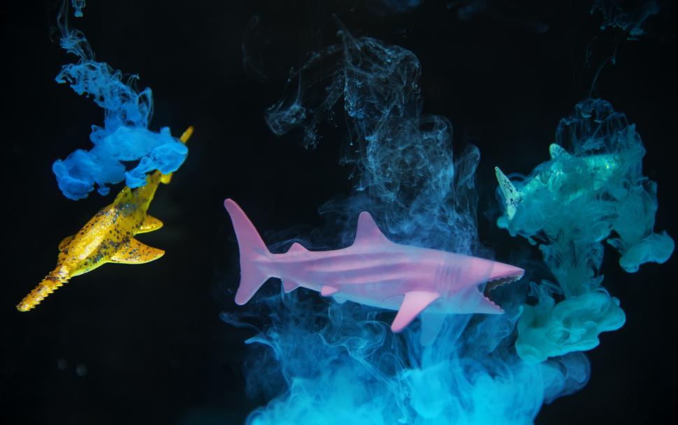 Free Image of An abstract pattern of green and blue ink swirling in water with miniature toy fishes 