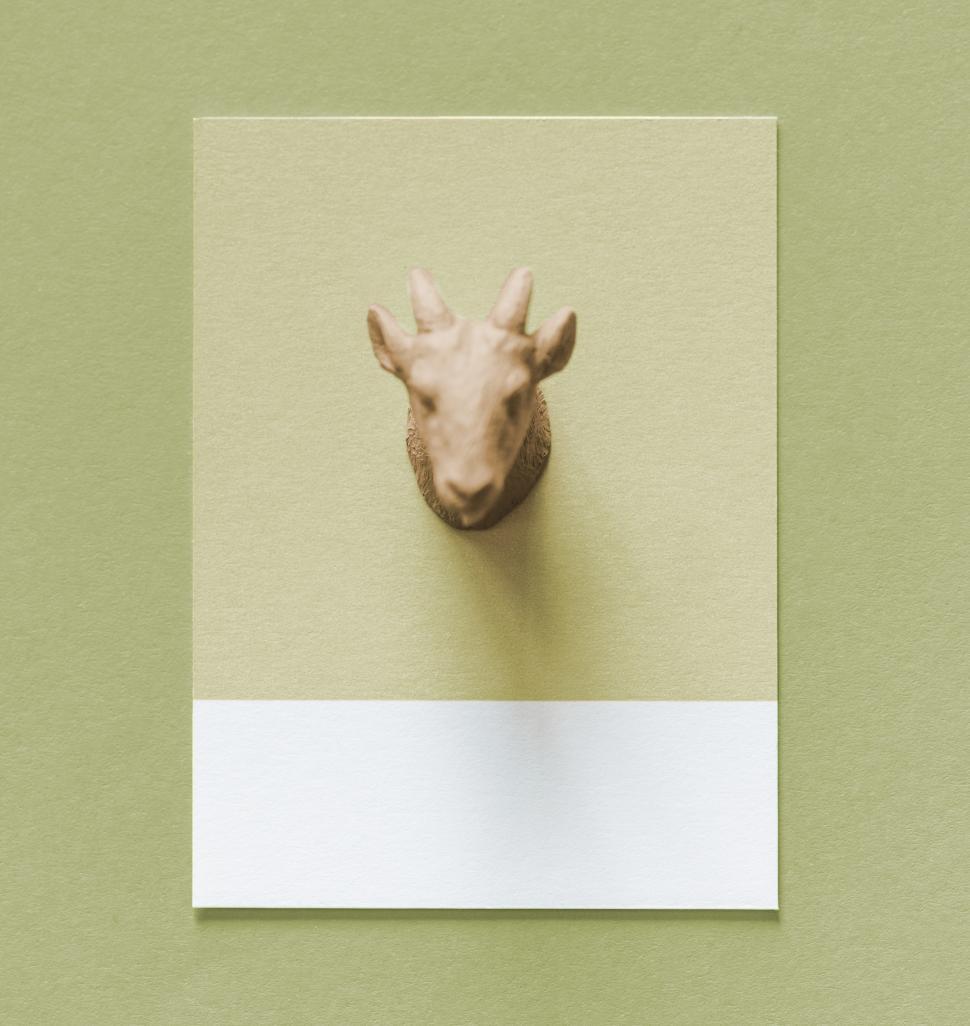 Free Image of Flay lay of a miniature toy goat s head on a spaced cardboard frame 