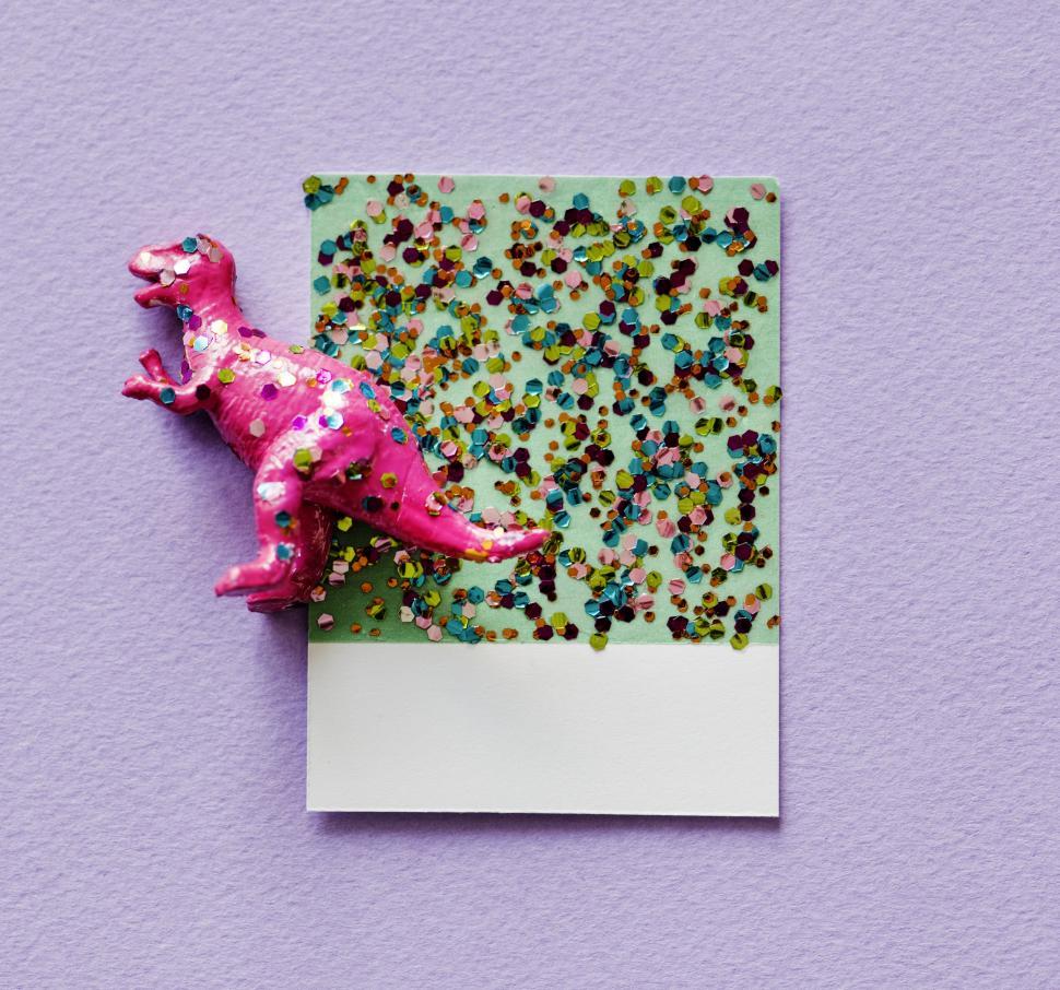 Free Image of Flay lay of a miniature glittery toy dinosaur on a spaced cardboard frame 