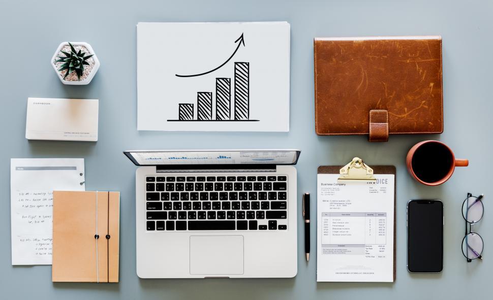 Free Image of Laptop and a coffee mug along with bar chart on the office table 