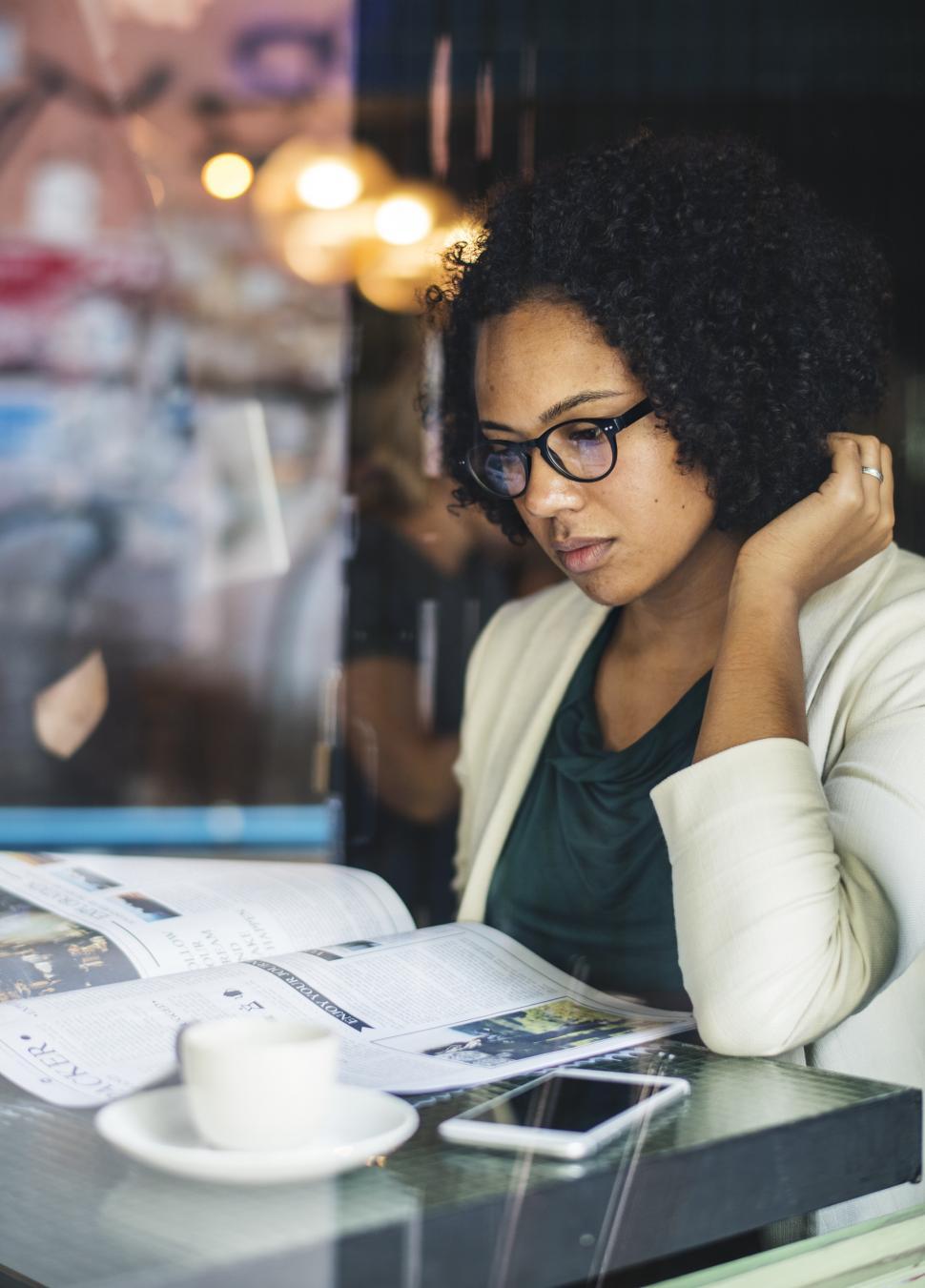 Free Image of A young woman reading magazine at a cafe 