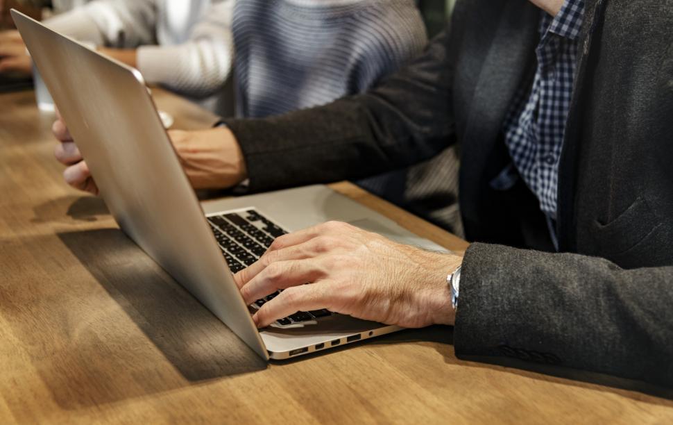 Free Image of Sitting at a table, typing on a laptop 
