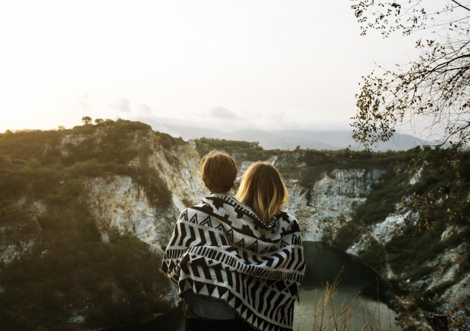 Free Image of Back view of two young women wrapped in a blanket looking at mountains 