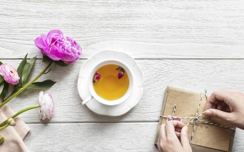 Free Image of Overhead view of a cup of herbal tea alongside a stack of envelopes being tied up 
