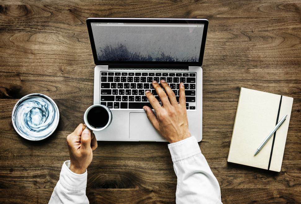 Free Image of Overhead view of a person s hand typing on laptop, with coffee 