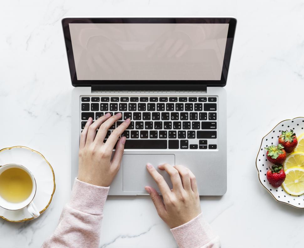 Free Image of View of hands on a laptop on marble surface 