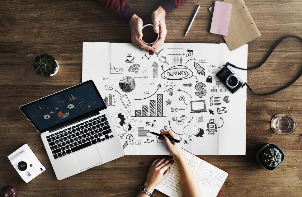 Free Image of Laptop and a coffee mug along with other items and hand drawn charts 
