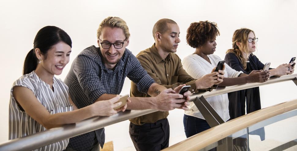 Free Image of Multiethnicity colleagues leaning and looking at their mobile phones 