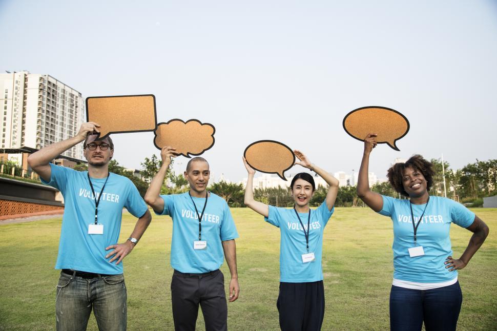 Free Image of A group of multiethnicity colleagues raising various cardboard speech bubble cutouts 
