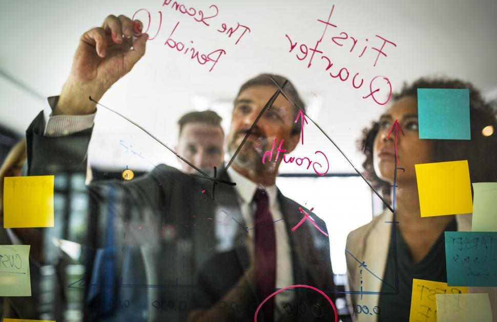 Free Image of A bearded Caucasian businessman drawing a graph on the glass panel 