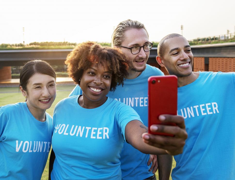 Free Image of A group of volunteers taking a group selfie with red mobile phone 