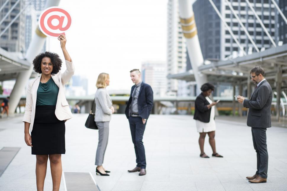Free Image of A young woman with curly hair hold a cardboard at sign    in her hand high with a smile 