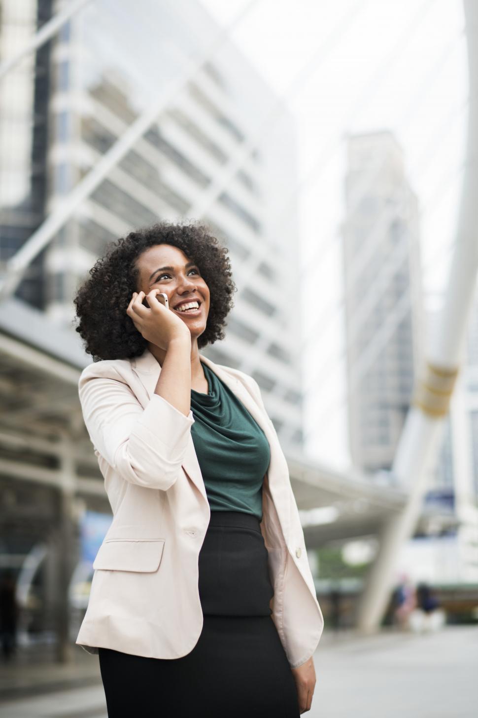 Free Image of A young woman outside in a city, speaking on a mobile phone 