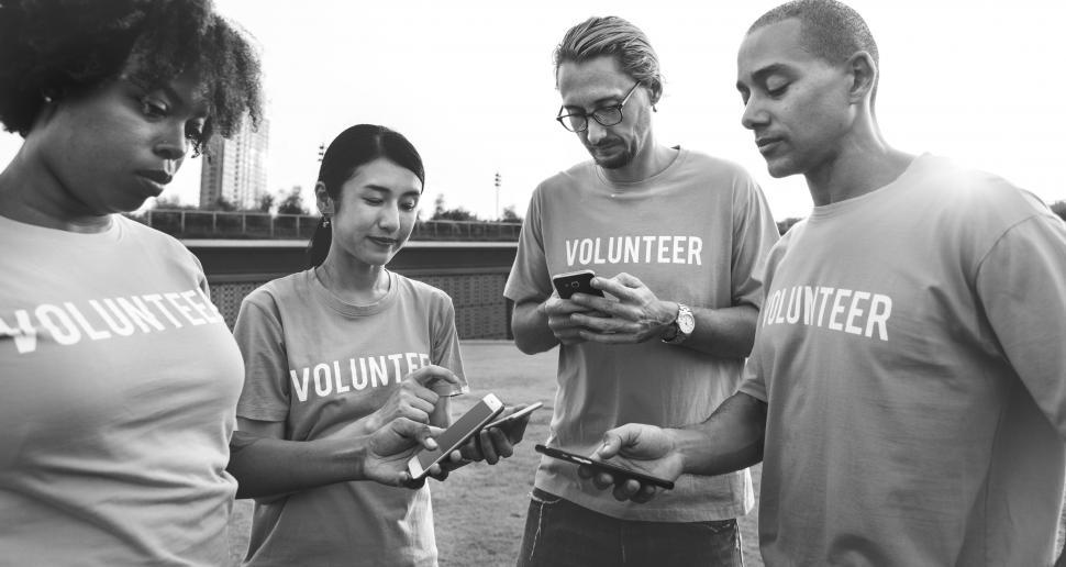 Free Image of Black and white photo of volunteers looking at their mobile phones 