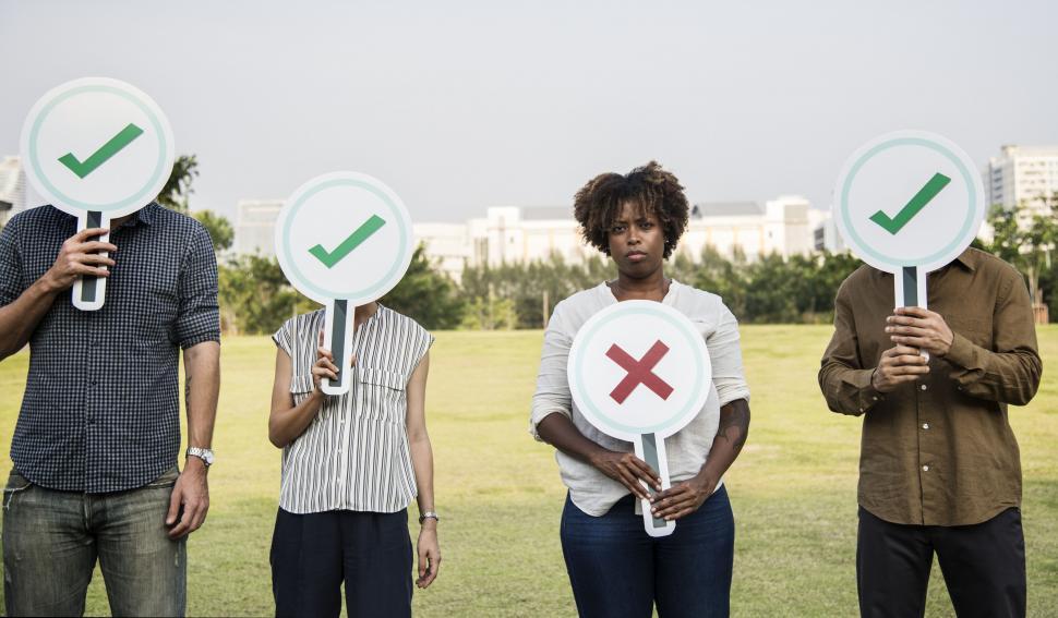 Free Image of Group of business people hiding their faces behind cardboard check mark and cross cardboard signs 