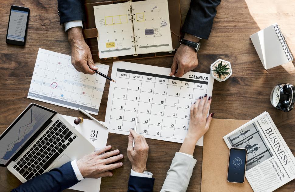 Free Image of Overhead view of people s hands pointing at a calendar on the table 
